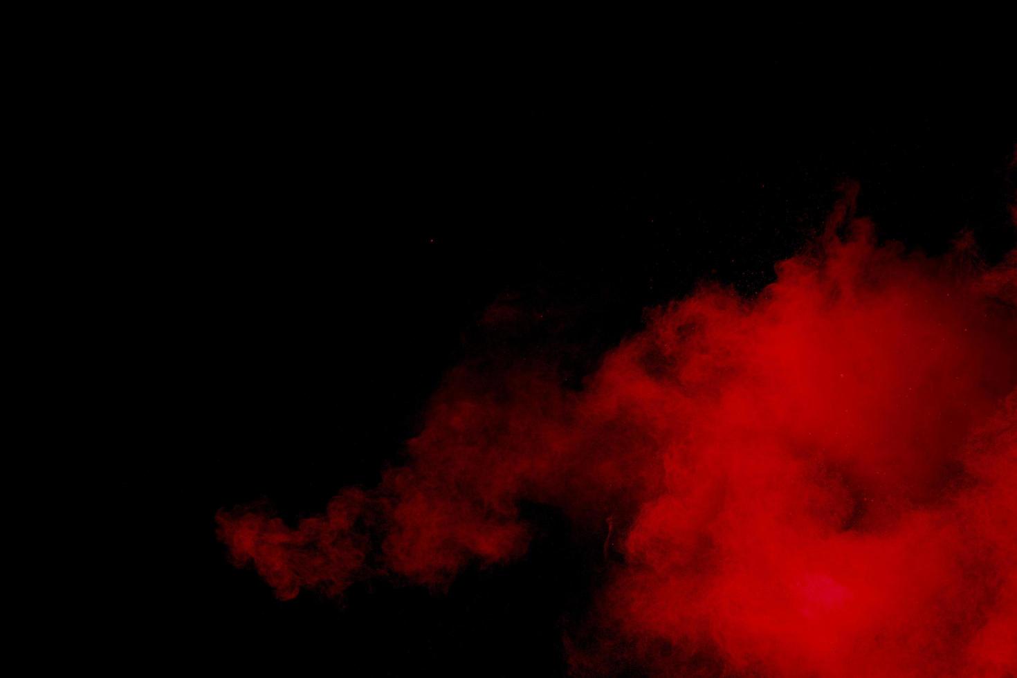 Red powder explosion on black background. Freeze motion of red dust particles splash. photo