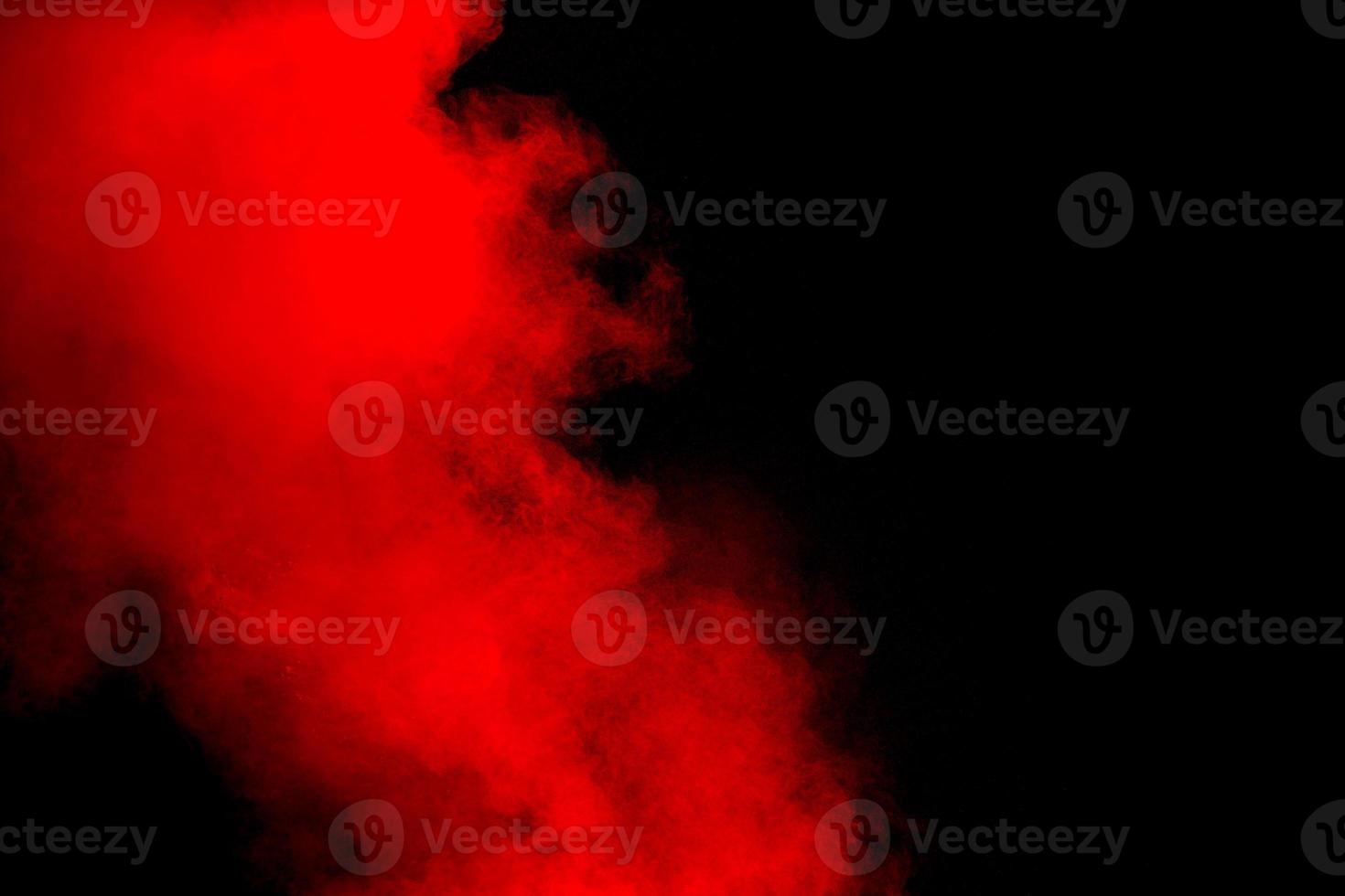 Red powder explosion on black background. Freeze motion of red dust particles splash. photo