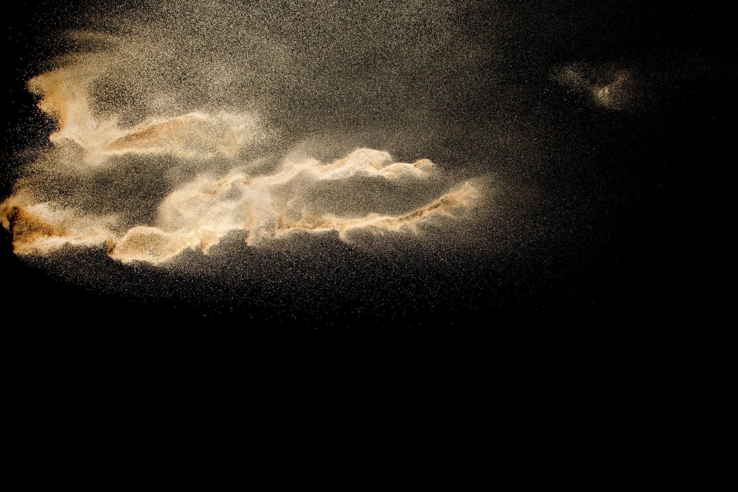 Brown colored sand splash against dark background. Dry river sand explosion isolated on black background. Abstract sand cloud. photo