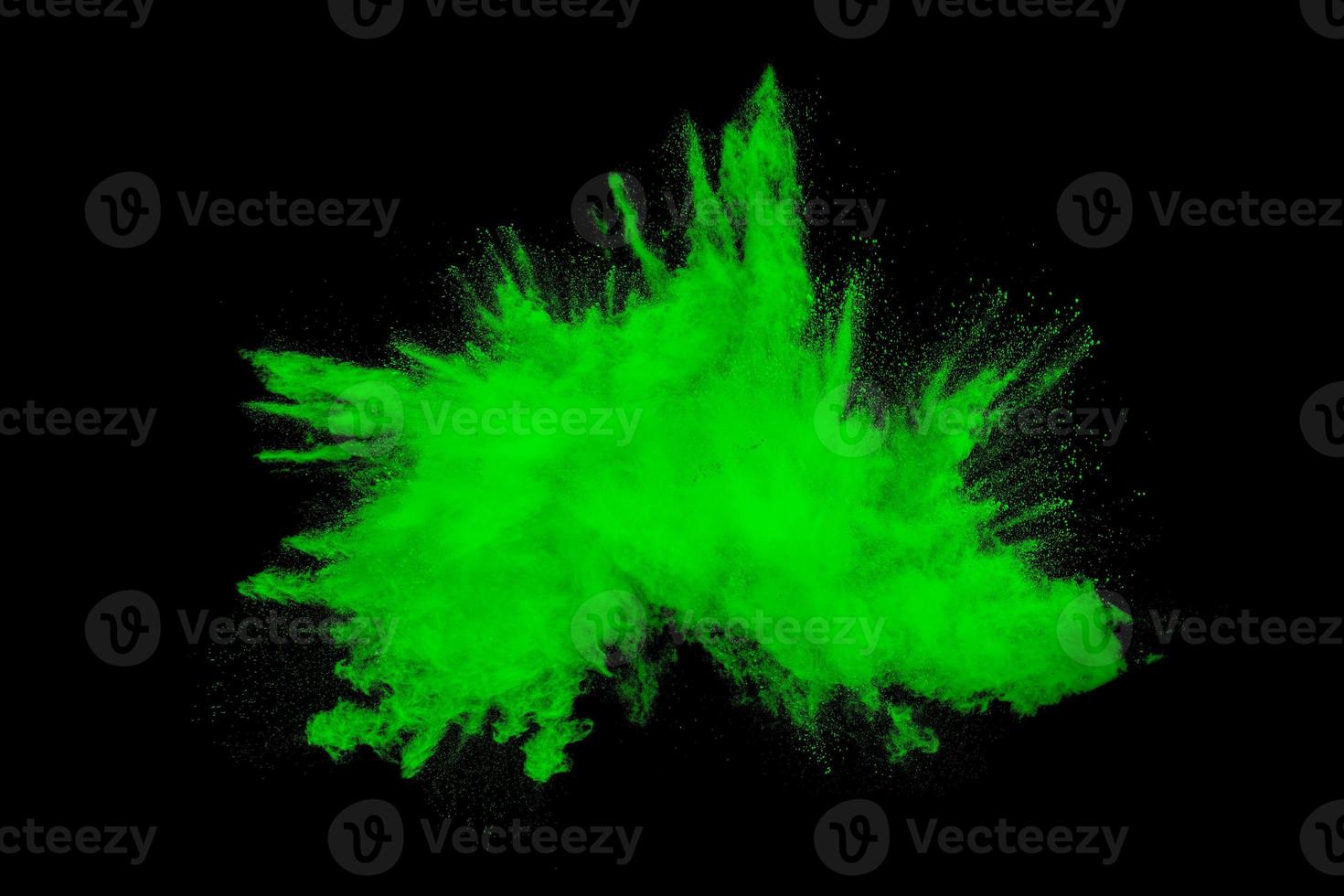 Green orange dust particles explosion on black background. Color powder dust splash. photo
