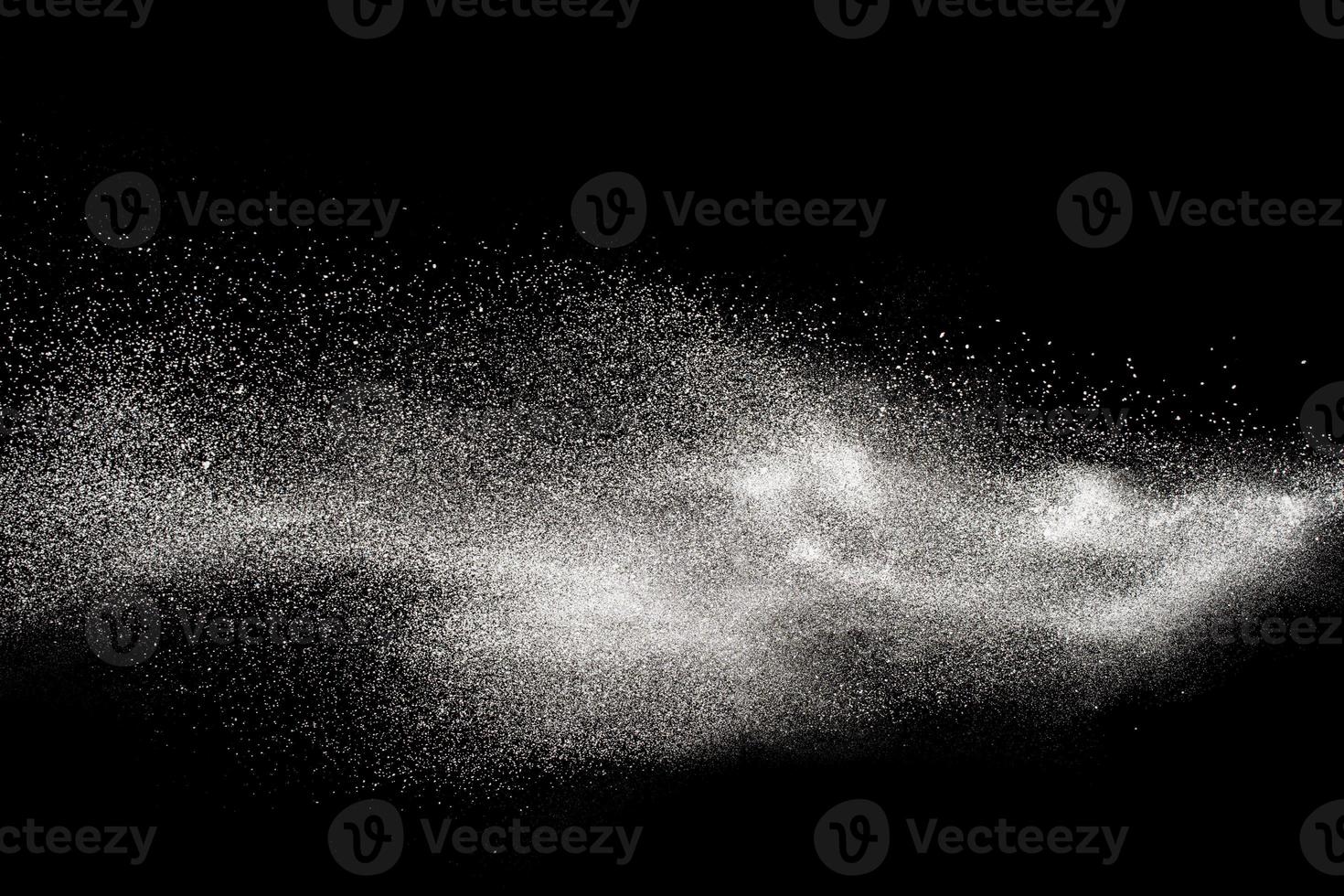 congelar el movimiento de partículas de polvo blanco sobre fondo negro. explosión de polvo blanco. foto