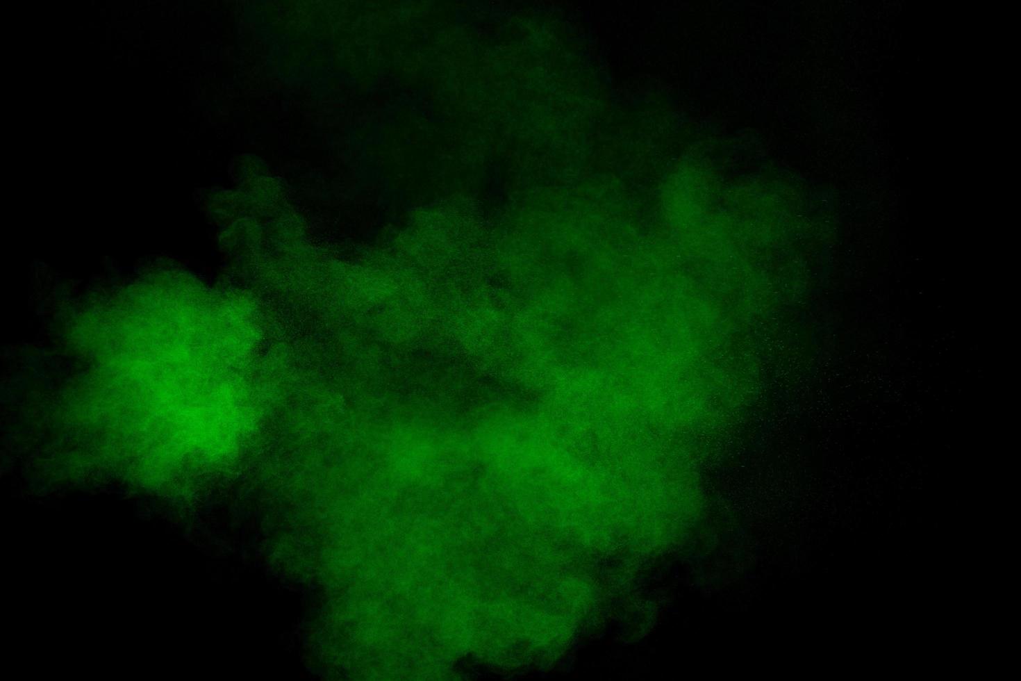 Abstract green powder explosion on black background.Freeze motion of green dust cloud. photo