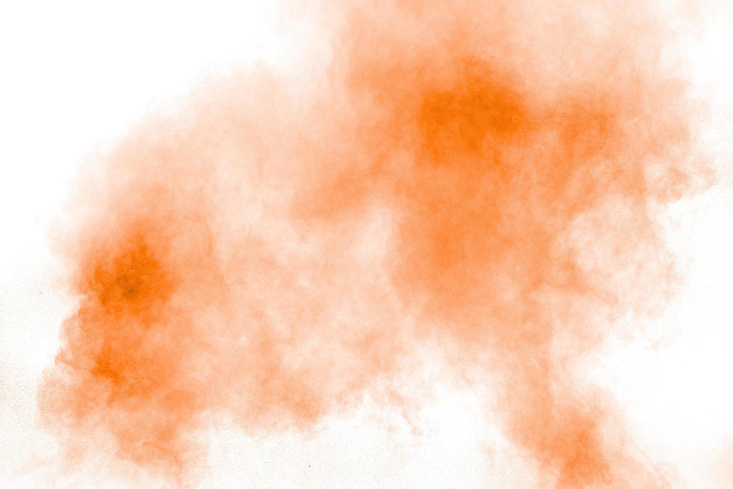 Abstract orange powder explosion on  white background. Freeze motion of orange dust splash. photo