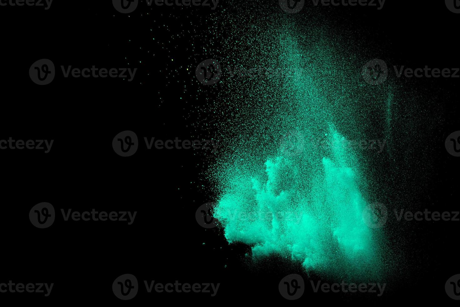 Abstract green dust explosion on black background. Abstract green powder splattered on background. photo