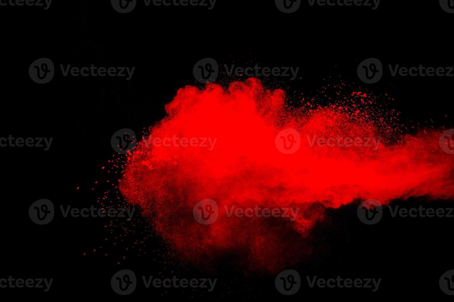 Red powder explosion cloud on black background. Freeze motion of red color dust  particles splashing. photo