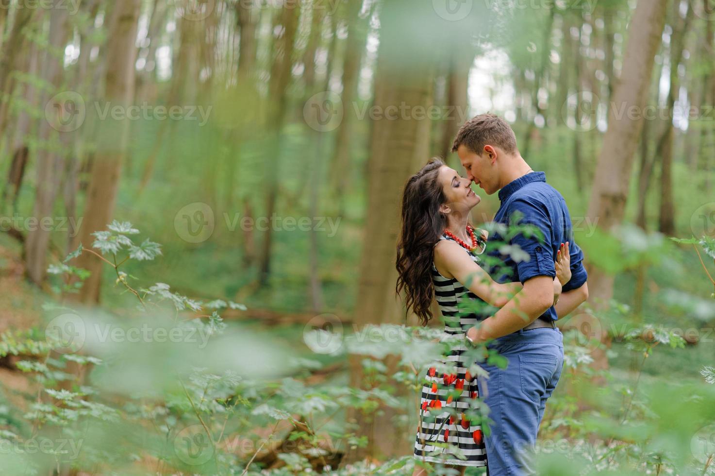 Young beautiful couple in love in the forest. A couple is hugging near a ravine among the trees. Free space. photo