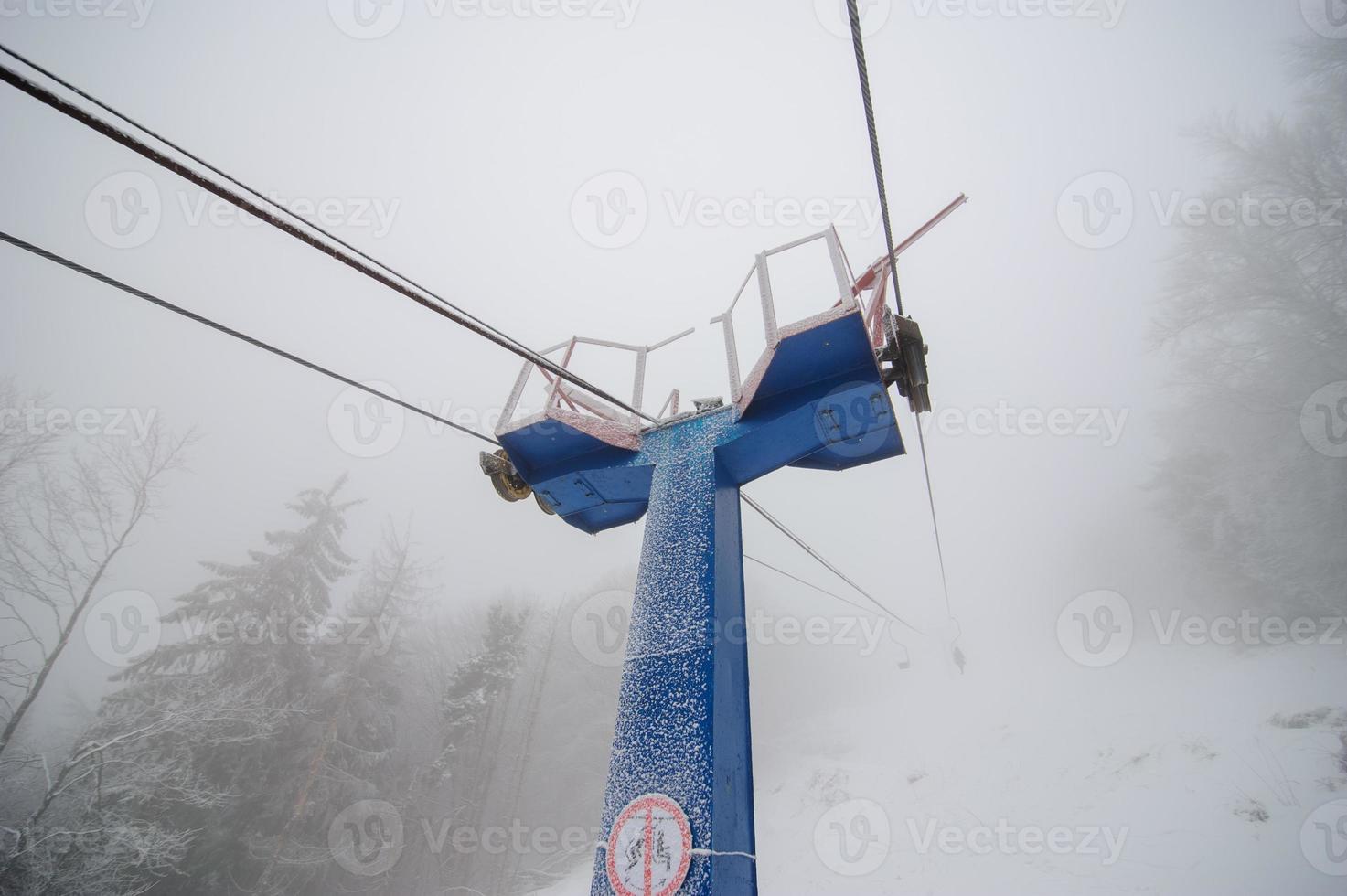 teleférico hasta la montaña en el bosque de invierno. el bosque está cubierto de nieve. clima nublado. mala visibilidad. foto