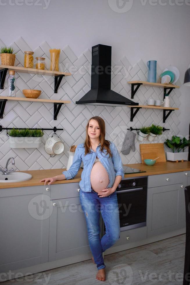 mujer embarazada de pie en su cocina foto