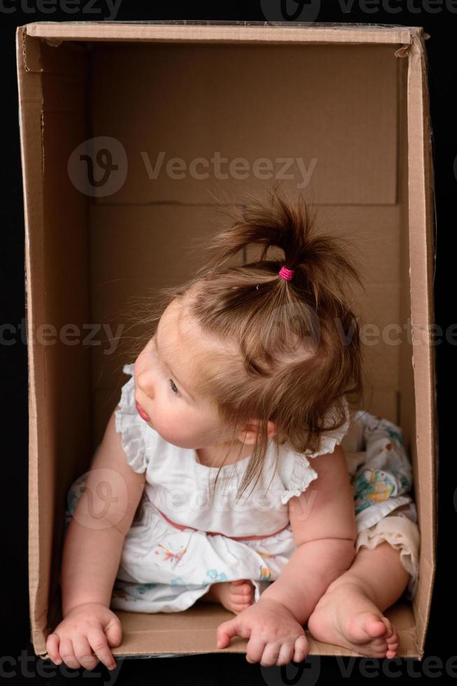 Little cute, beautiful girl sits in a box. photo