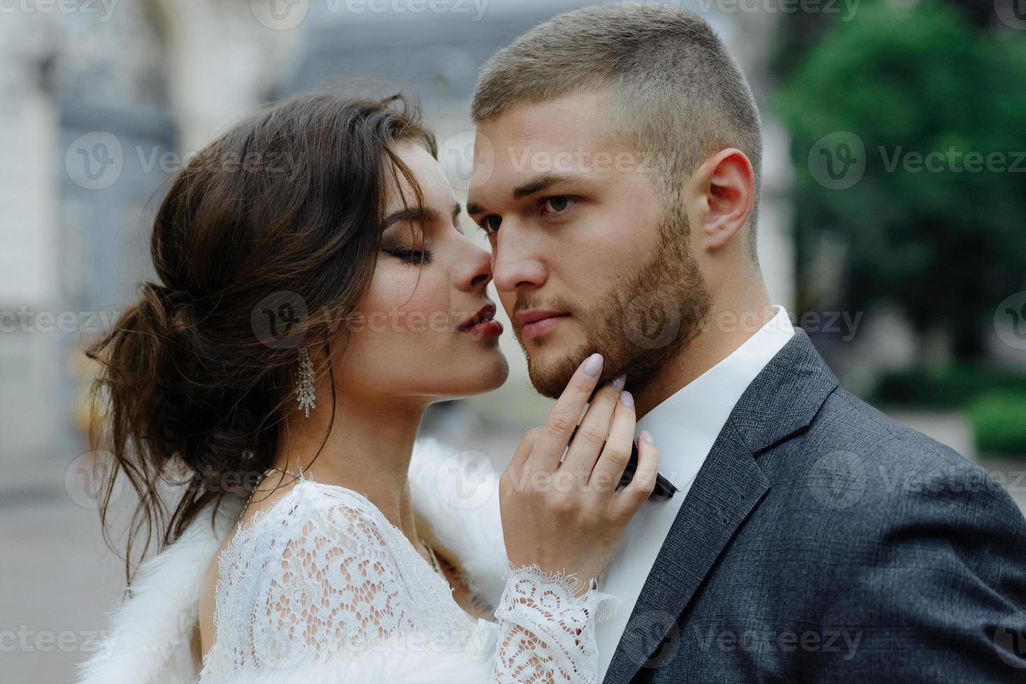 the groom in a gray suit and the bride in a gray dress look at each other, closeup portrait photo