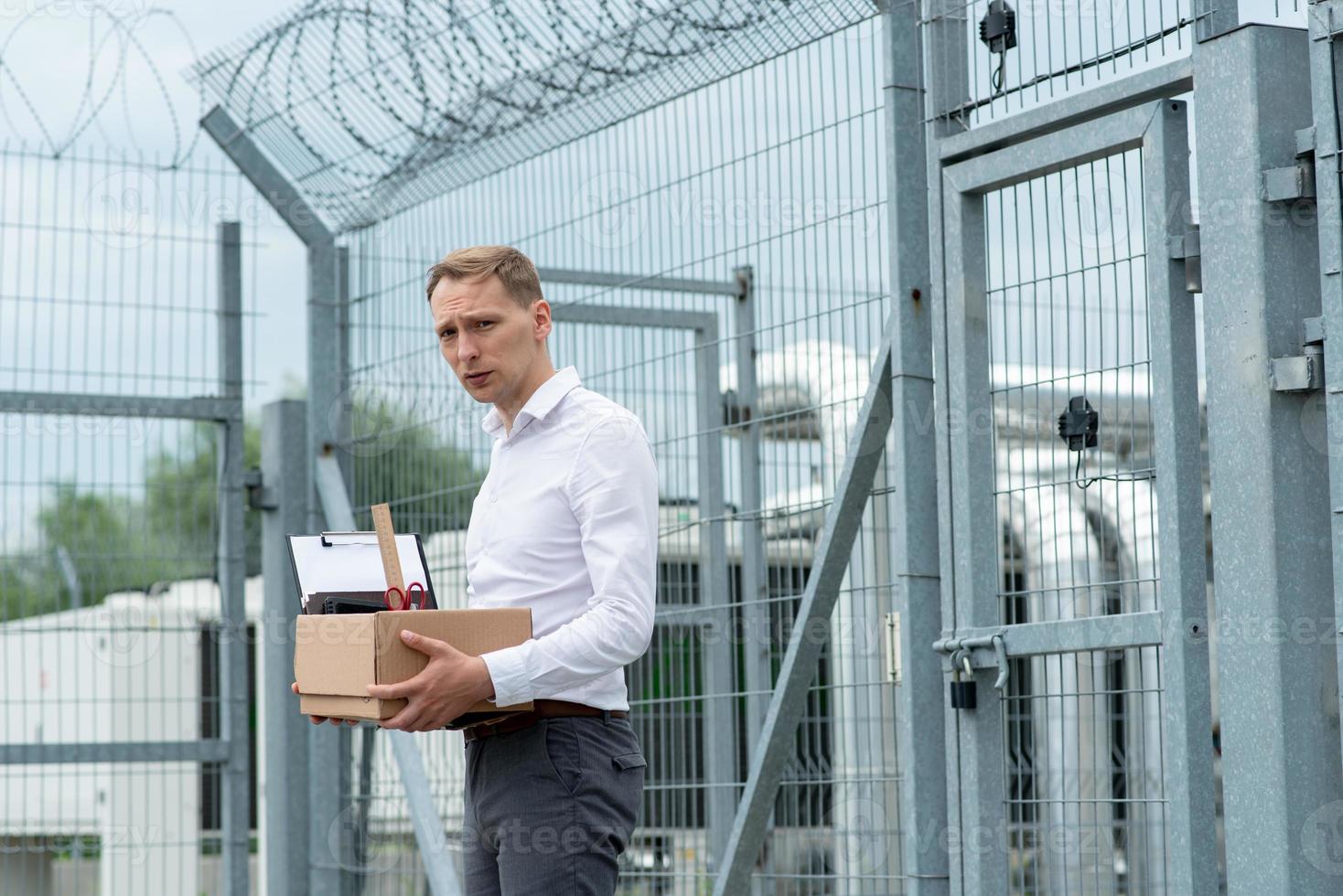 The businessman got out of prison with his things and is thinking about what to do next. A man stands near the exit from the prison. photo