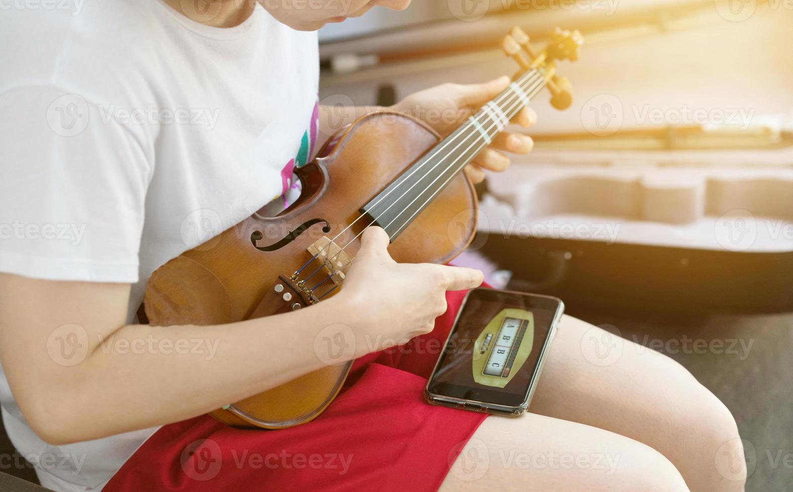 niña mujer afinar su violín uso teléfono eléctrico foto