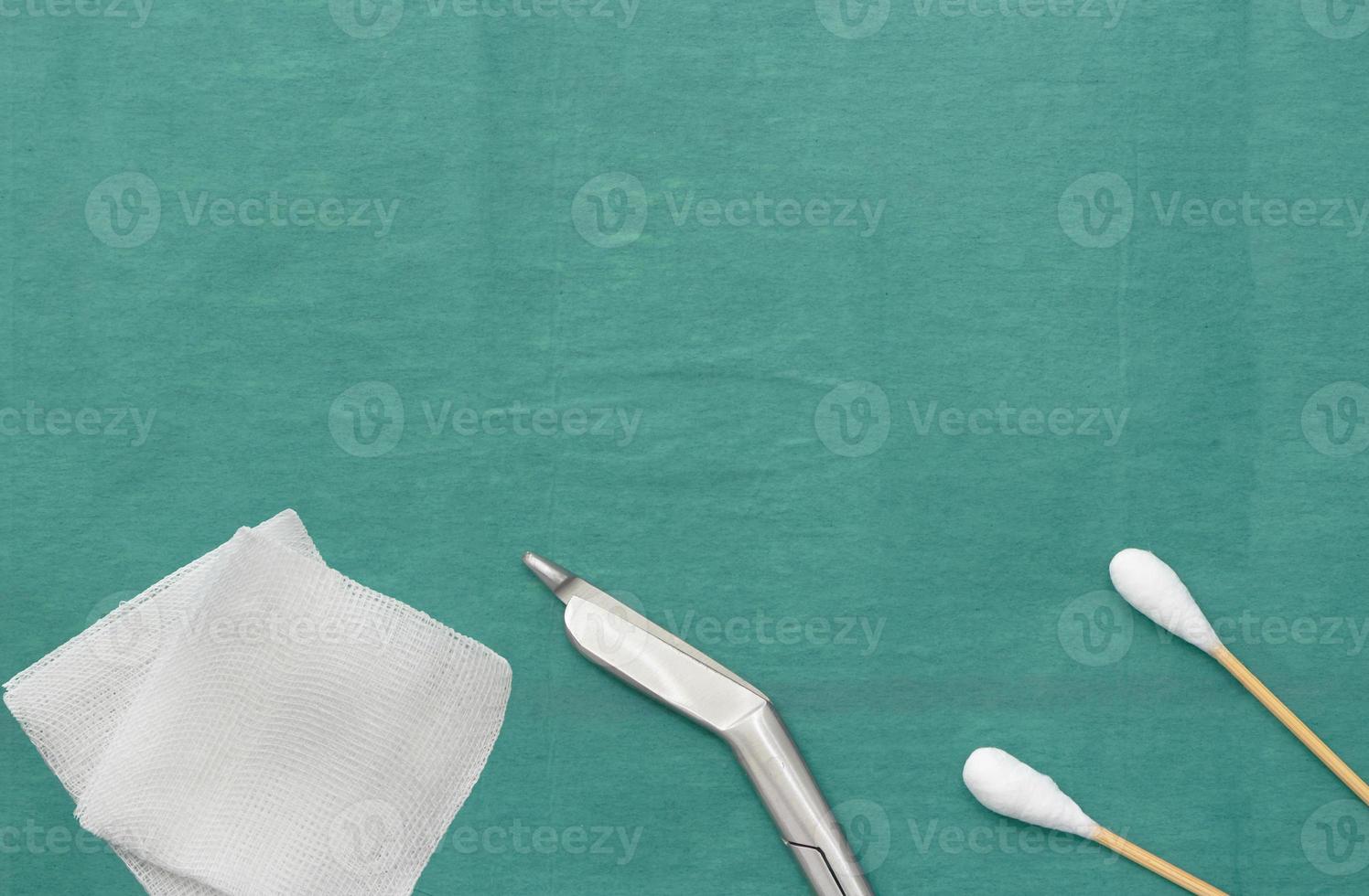 Gauze, scissors and swab cotton bus sticks on green medical surgical dress photo