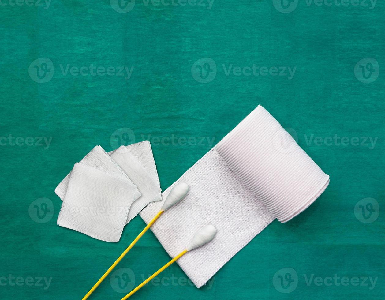 tools include swabs,roll gauze and blood gauze on green surgical dress  for clean wound with copy space photo