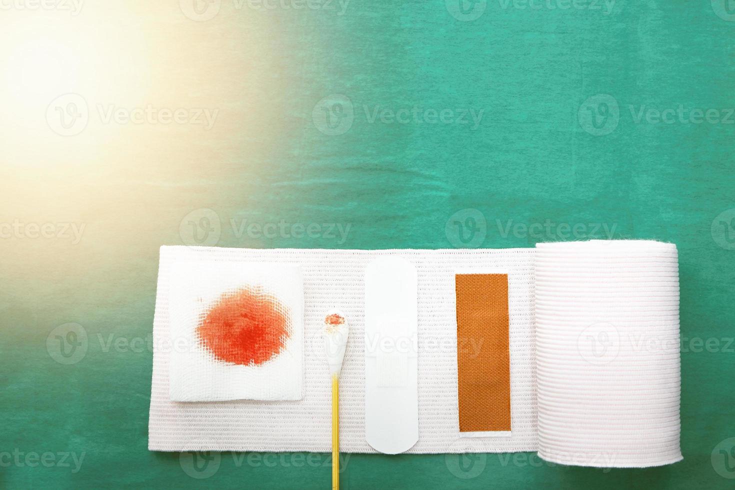 tools includes plaster,swab,blood gauze and roll gauze on green surgical dress for clean wound with copy space photo