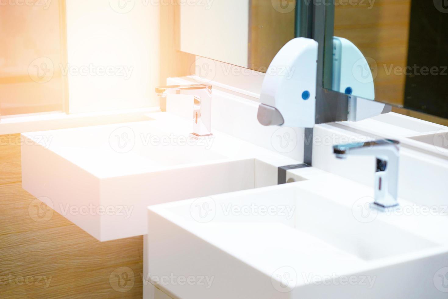 White ceramic sink and water tap with soap dispenser in bath room or toilet photo