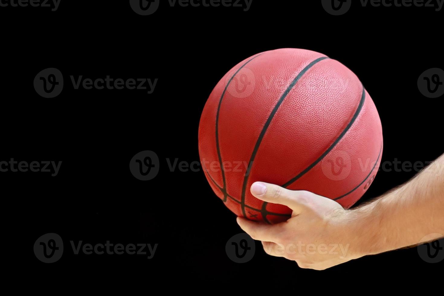 basketball ball in a man's hand on black background photo