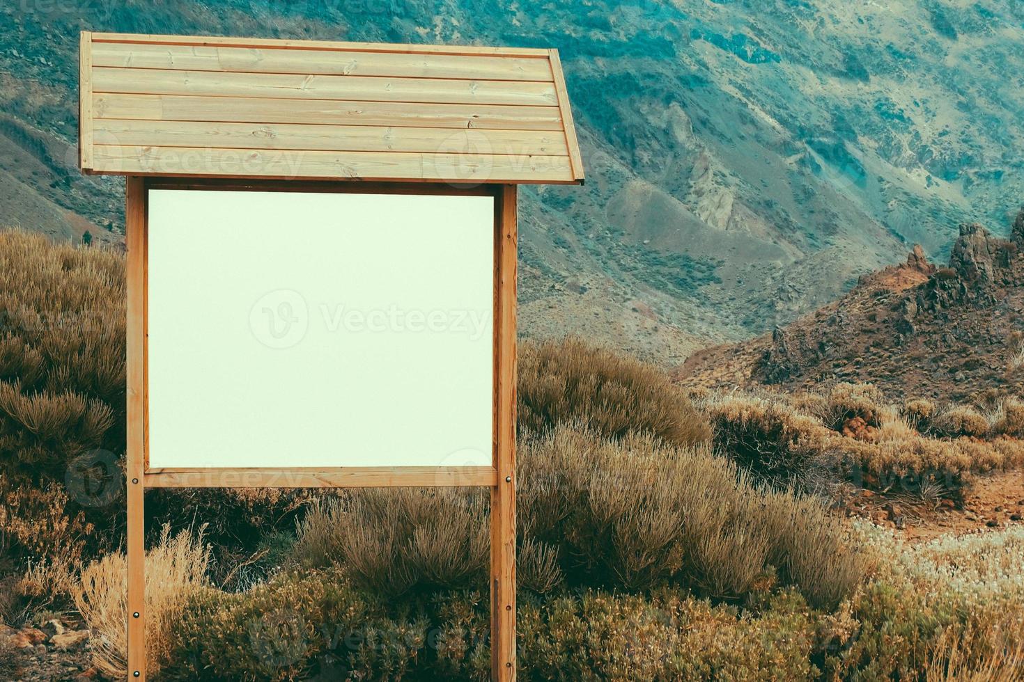 Wooden billboard with blank panel in a mountain landscape photo