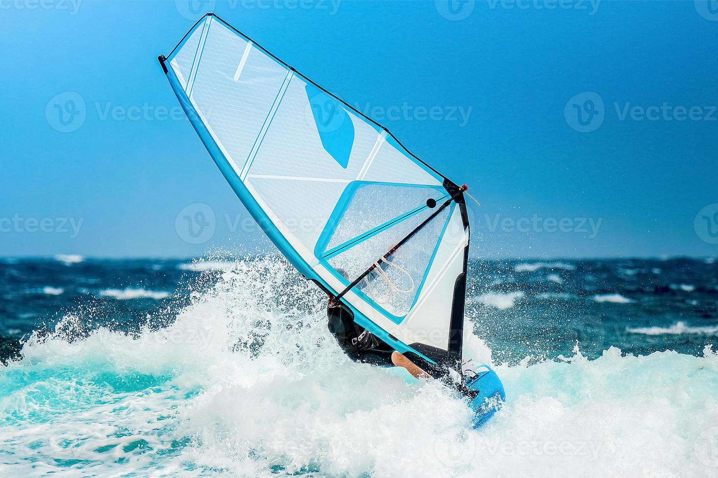 windsurfer riding the waves during the holidays with a white sail on the atlantic blue ocean water photo