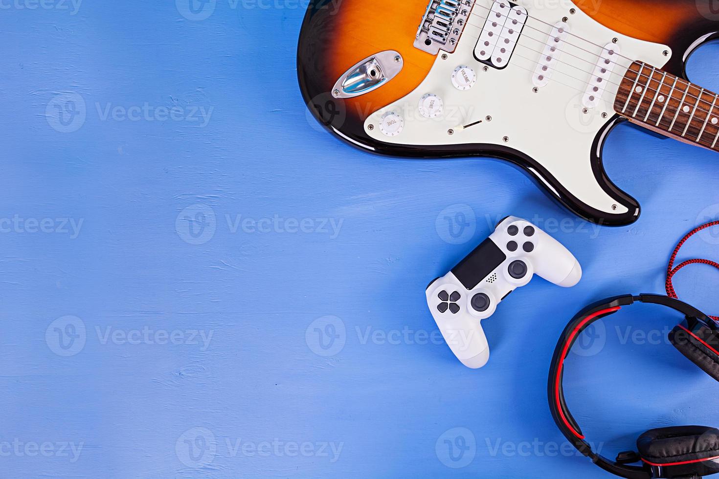 Electric guitar, joystick, headphones. Pop culture media attributes. Top view. photo