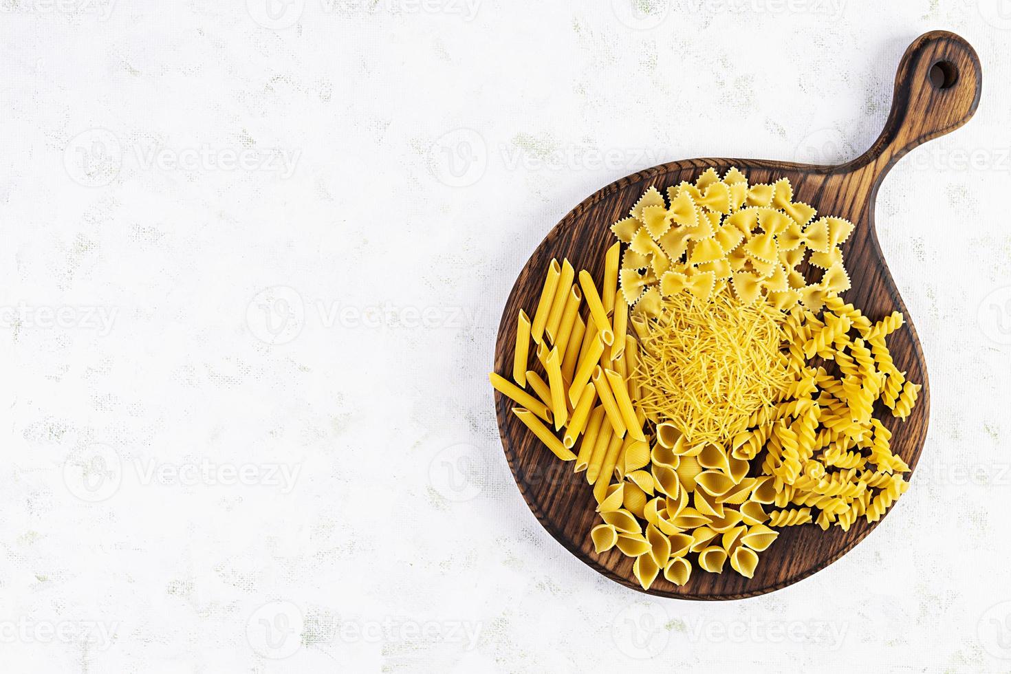 Different dry pasta on a wooden background. Top view photo