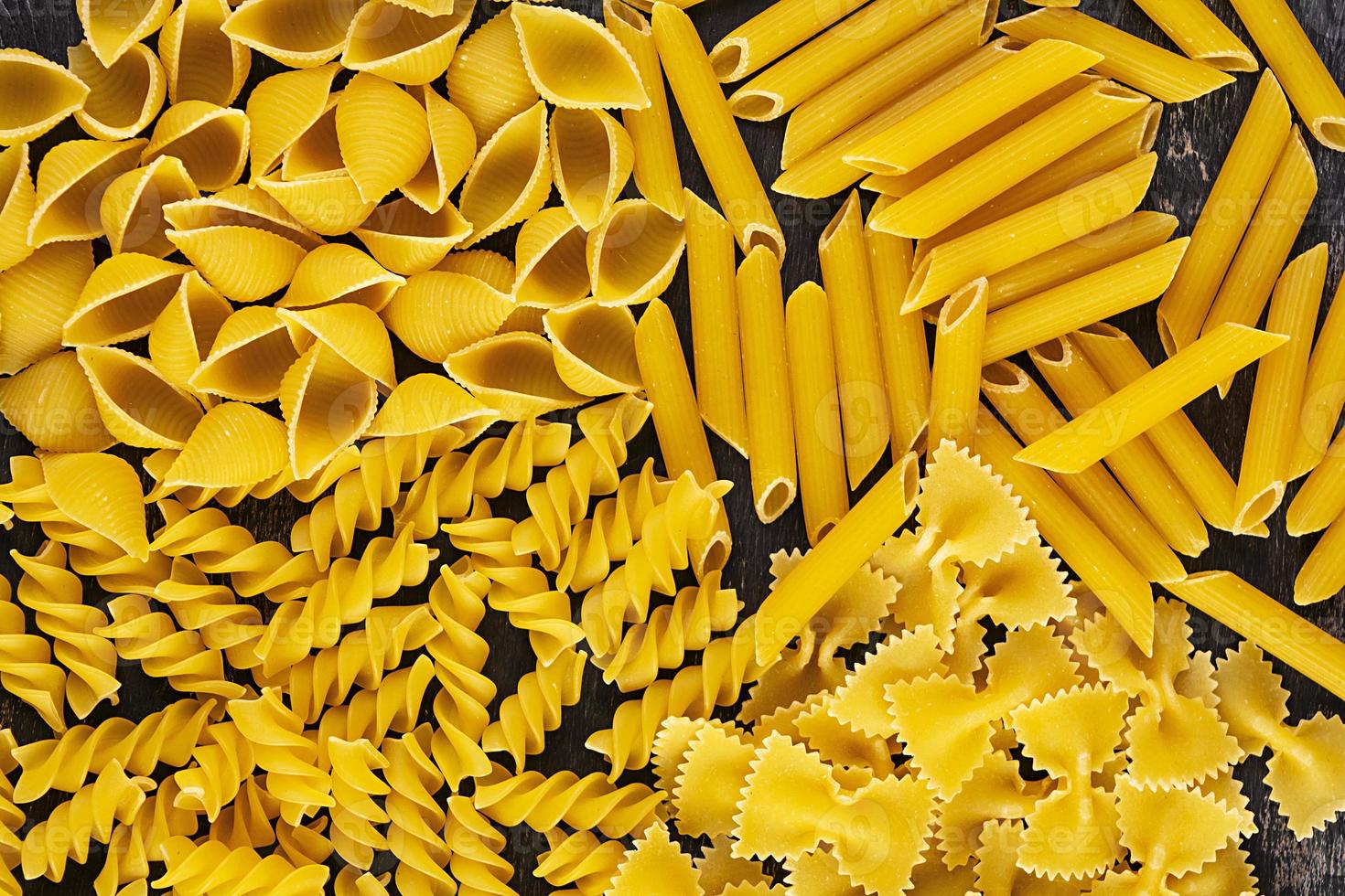 Different dry pasta on a wooden background. Top view photo