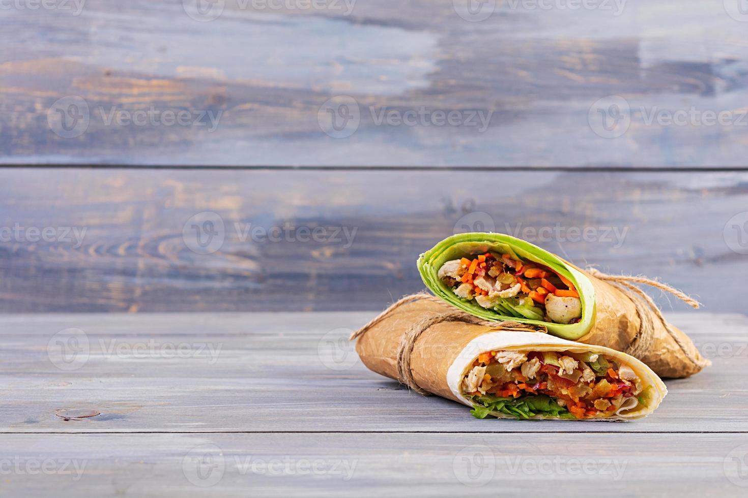Delicious shawarma sandwich with chicken on wooden background photo