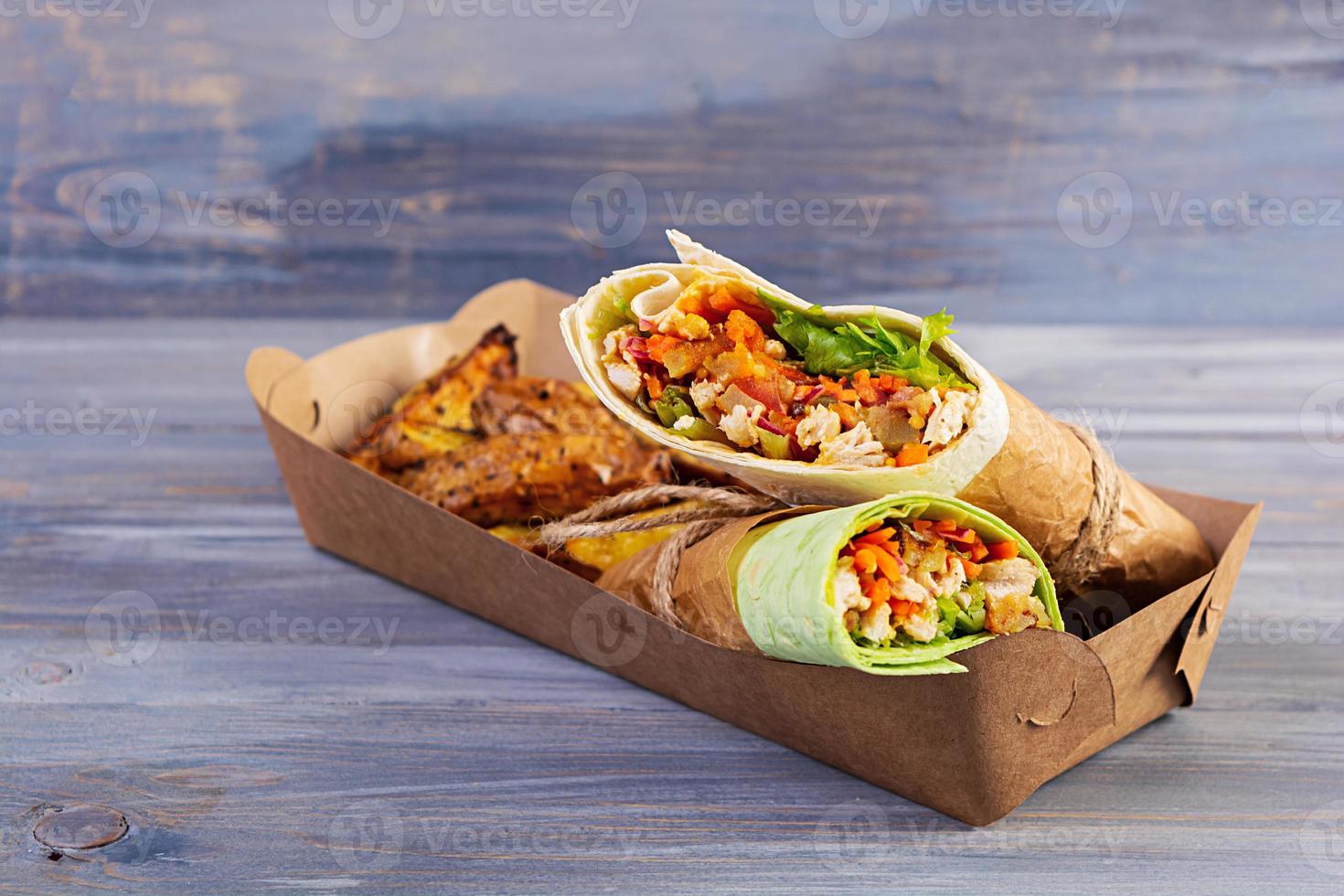 Delicious shawarma sandwich with chicken and potato on wooden background photo