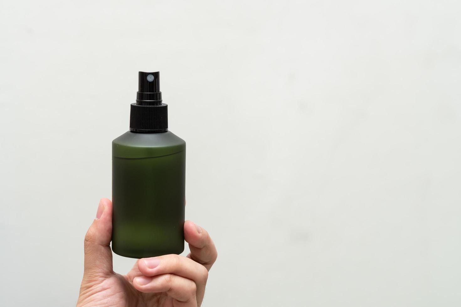Green cosmetic bottle with label isolated on white background. Close up aroma spray bottle. Concept of organic cruelty free. Natural organic spa cosmetics concept. photo
