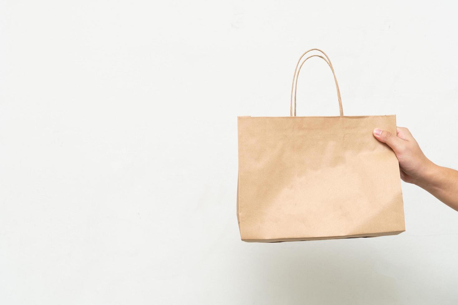 Hand with Kraft paper bag isolated on white background. save the world, reduce global warming photo