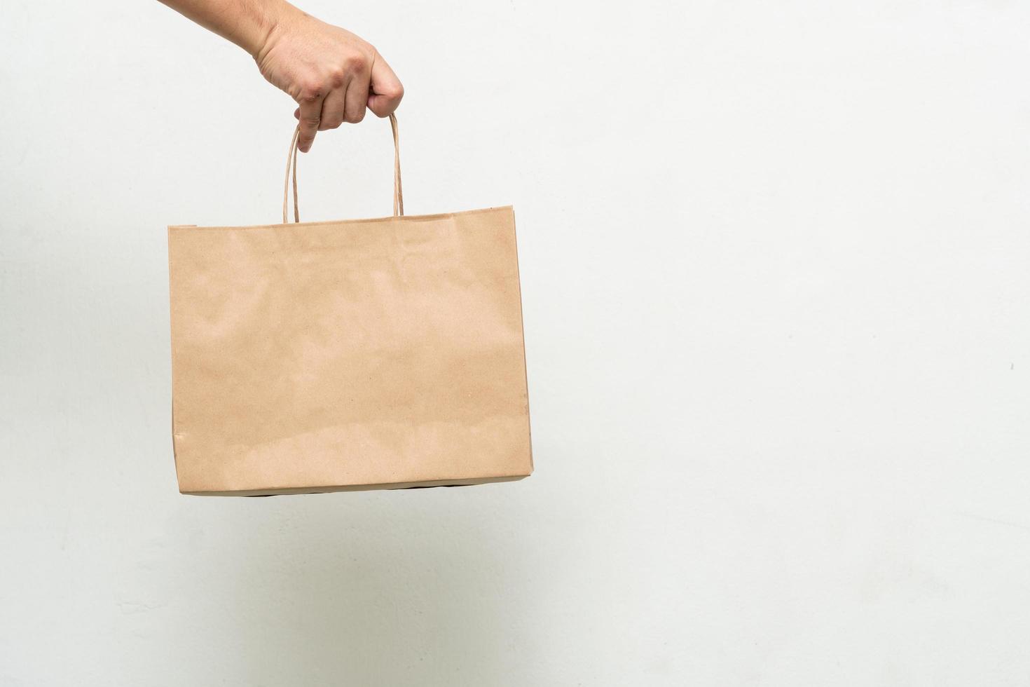 Hand with Kraft paper bag isolated on white background. save the world, reduce global warming photo