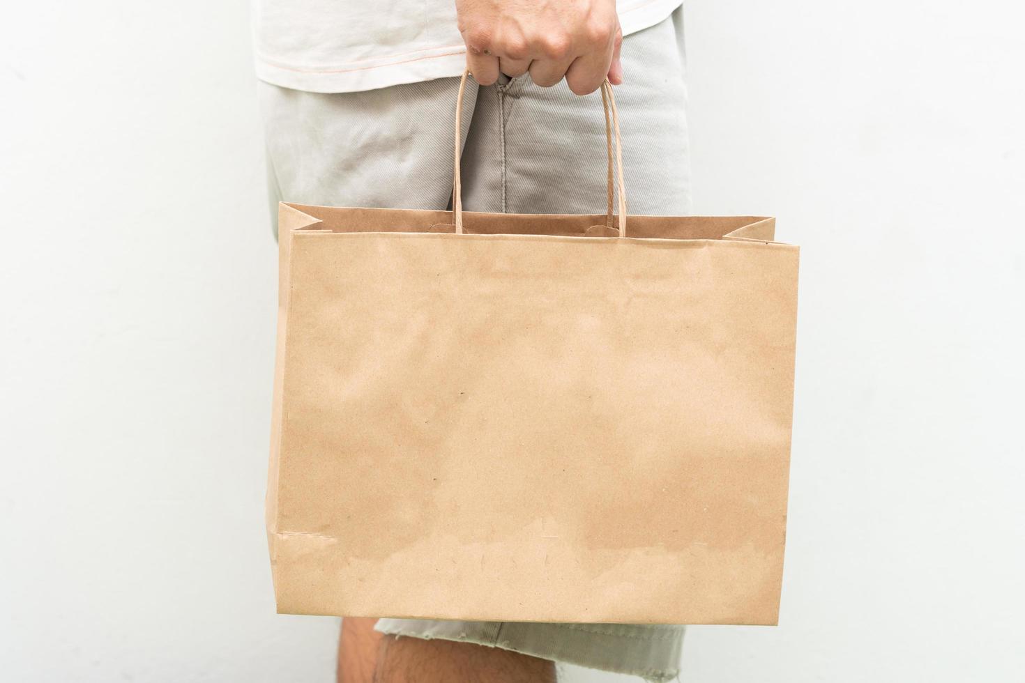 Hand with Kraft paper bag isolated on white background. save the world, reduce global warming photo