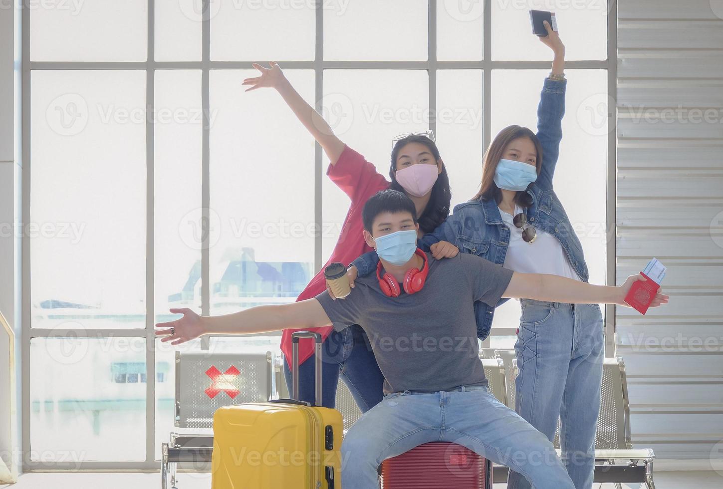 Happy young asian traveler group wearing face mask with suitcases celebration together before having fun trip on holiday at public terminal station. New normal travel concept, selective focus. photo