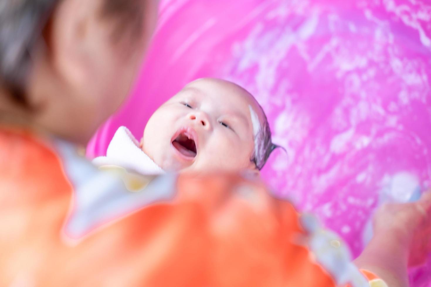 mamá asiática ducha al bebé para limpiar la suciedad dar al niño en un recipiente de baño para la limpieza estilo de vida familiar entre la madre y el niño utilizado para la ducha del bebé productos de crema champús lociones y productos para el cuidado del bebé foto