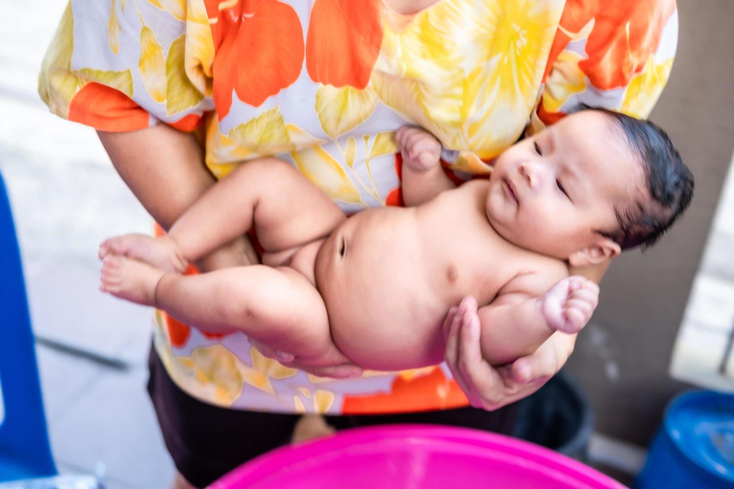 Asian mom shower baby to clean dirt give child in bath container for cleanliness lifestyle family between mother and child Used for baby shower cream products shampoos lotions and baby care product photo