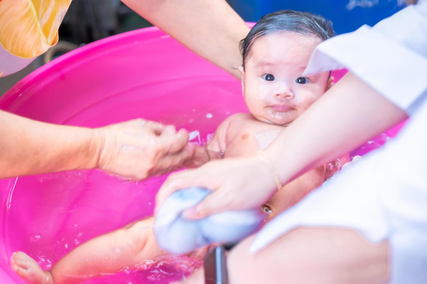 Asian mom shower baby to clean dirt give child in bath container for cleanliness lifestyle family between mother and child Used for baby shower cream products shampoos lotions and baby care product photo