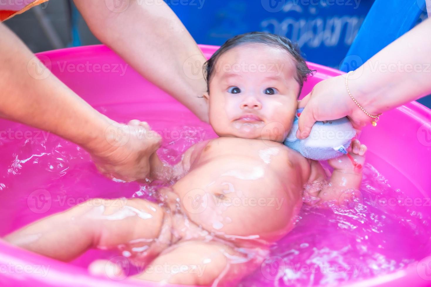 mamá asiática ducha al bebé para limpiar la suciedad dar al niño en un recipiente de baño para la limpieza estilo de vida familiar entre la madre y el niño utilizado para la ducha del bebé productos de crema champús lociones y productos para el cuidado del bebé foto