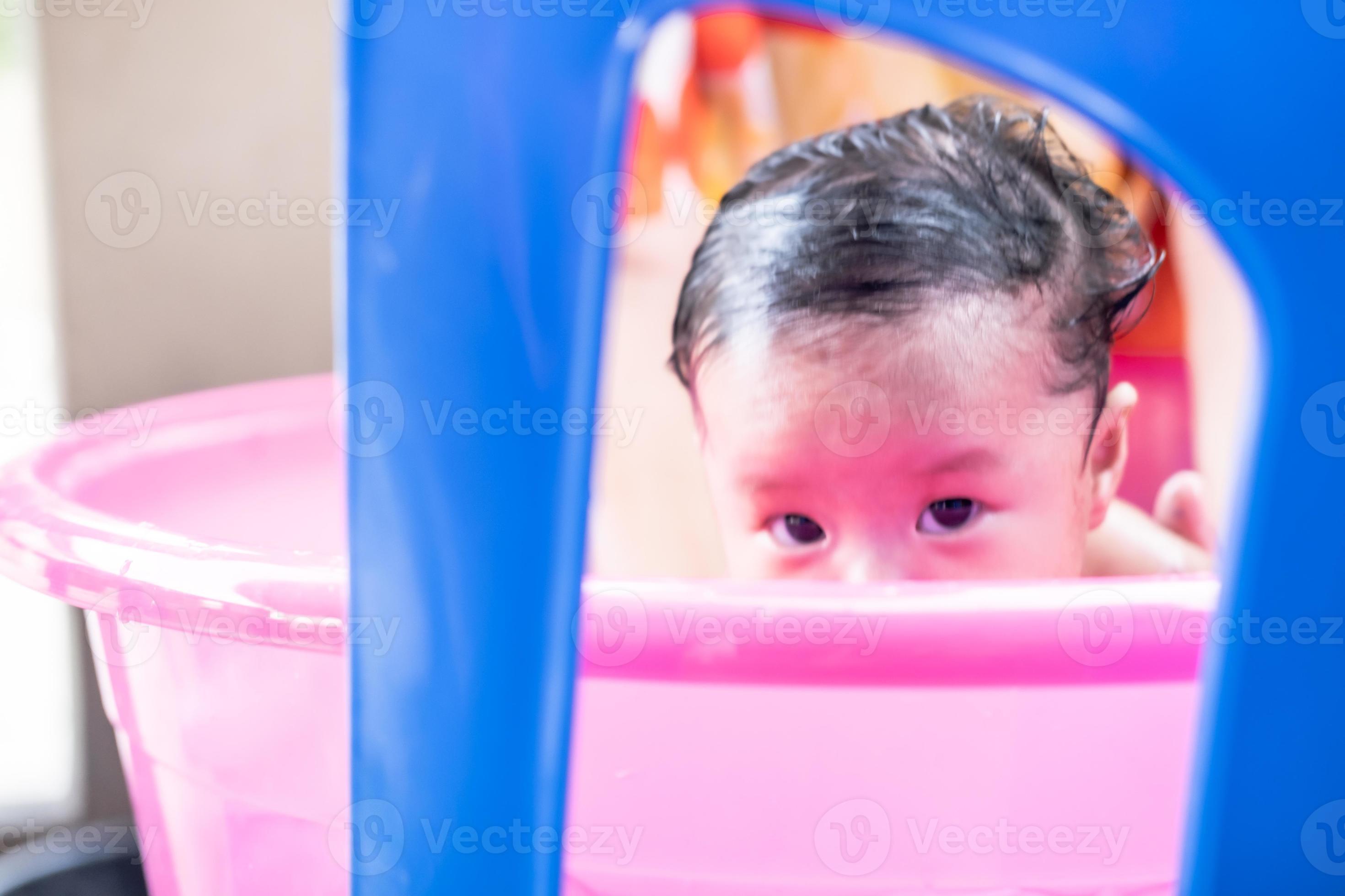 mamá asiática ducha al bebé para limpiar la suciedad dar al niño en un  recipiente de