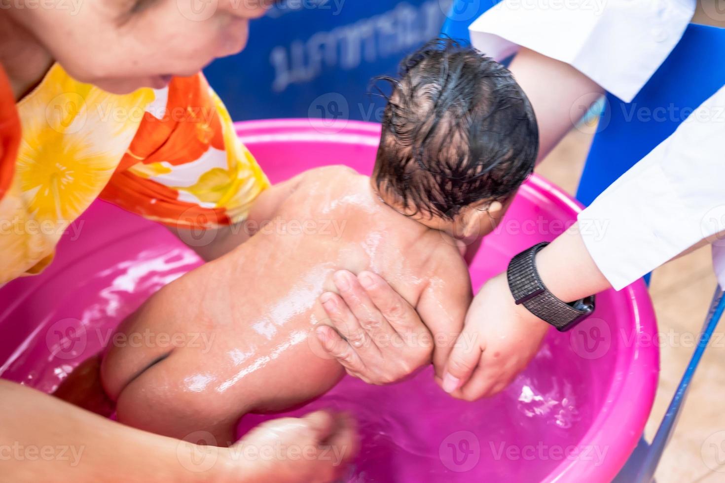 mamá asiática ducha al bebé para limpiar la suciedad dar al niño en un  recipiente de