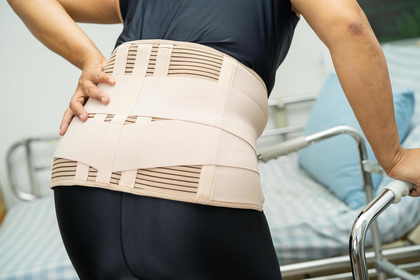 Asian lady patient wearing back pain support belt for orthopedic lumbar with walker. photo