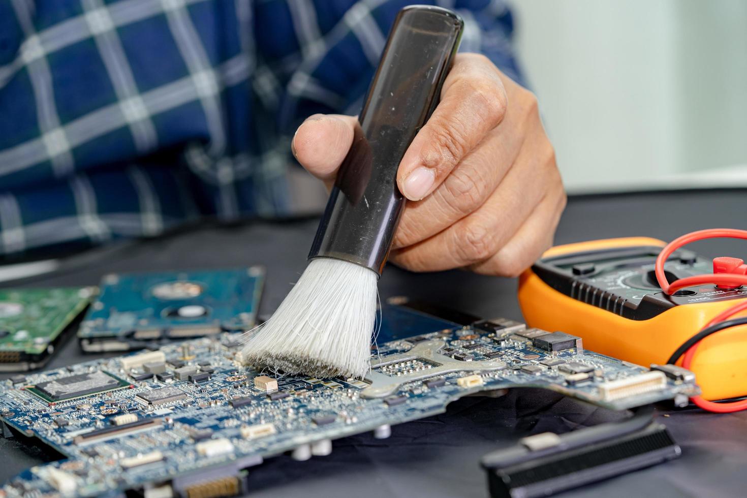 El técnico usa un cepillo y una bola de aire para limpiar el polvo en la placa de circuito de la computadora. reparación de tecnología de actualización y mantenimiento. foto