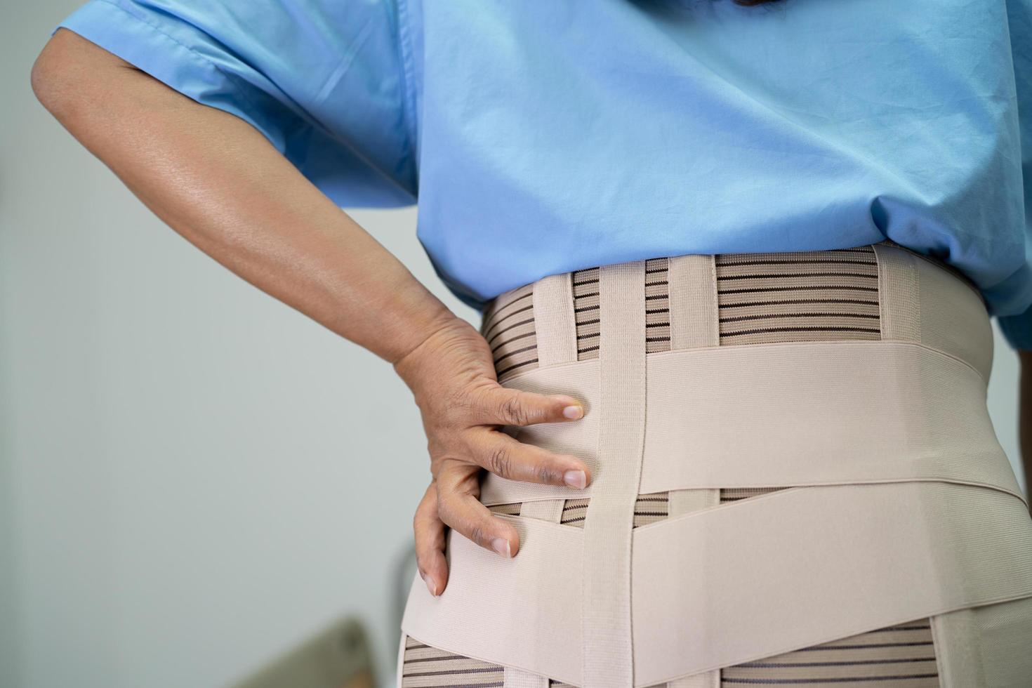 Asian lady patient wearing back pain support belt for orthopedic lumbar with walker. photo