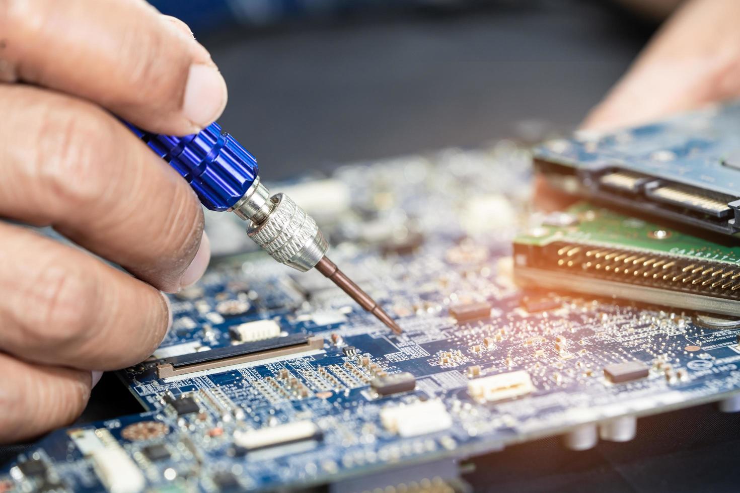 Technician repairing inside of printed circuit board PCB by soldering iron. Integrated Circuit. the concept of data, hardware, technician and technology. photo