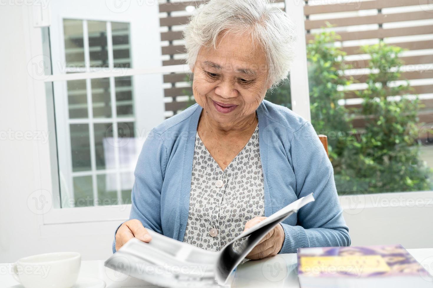 Asian senior or elderly old lady woman patient reading a book while sitting on bed in nursing hospital ward, healthy strong medical concept. photo