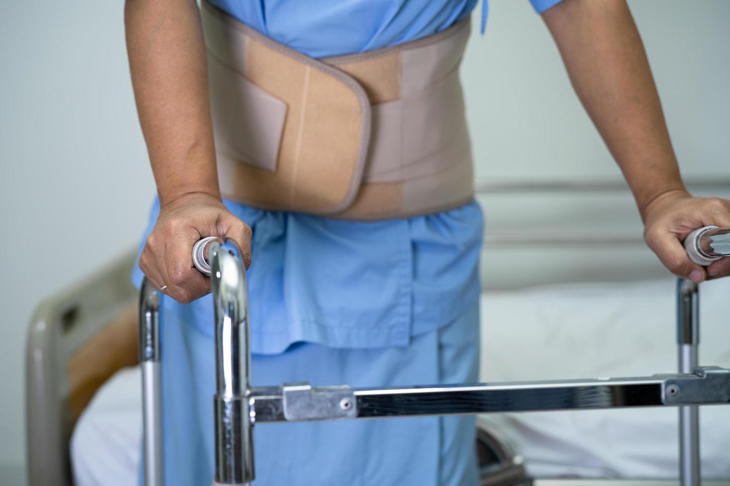 Asian lady patient wearing back pain support belt for orthopedic lumbar with walker. photo