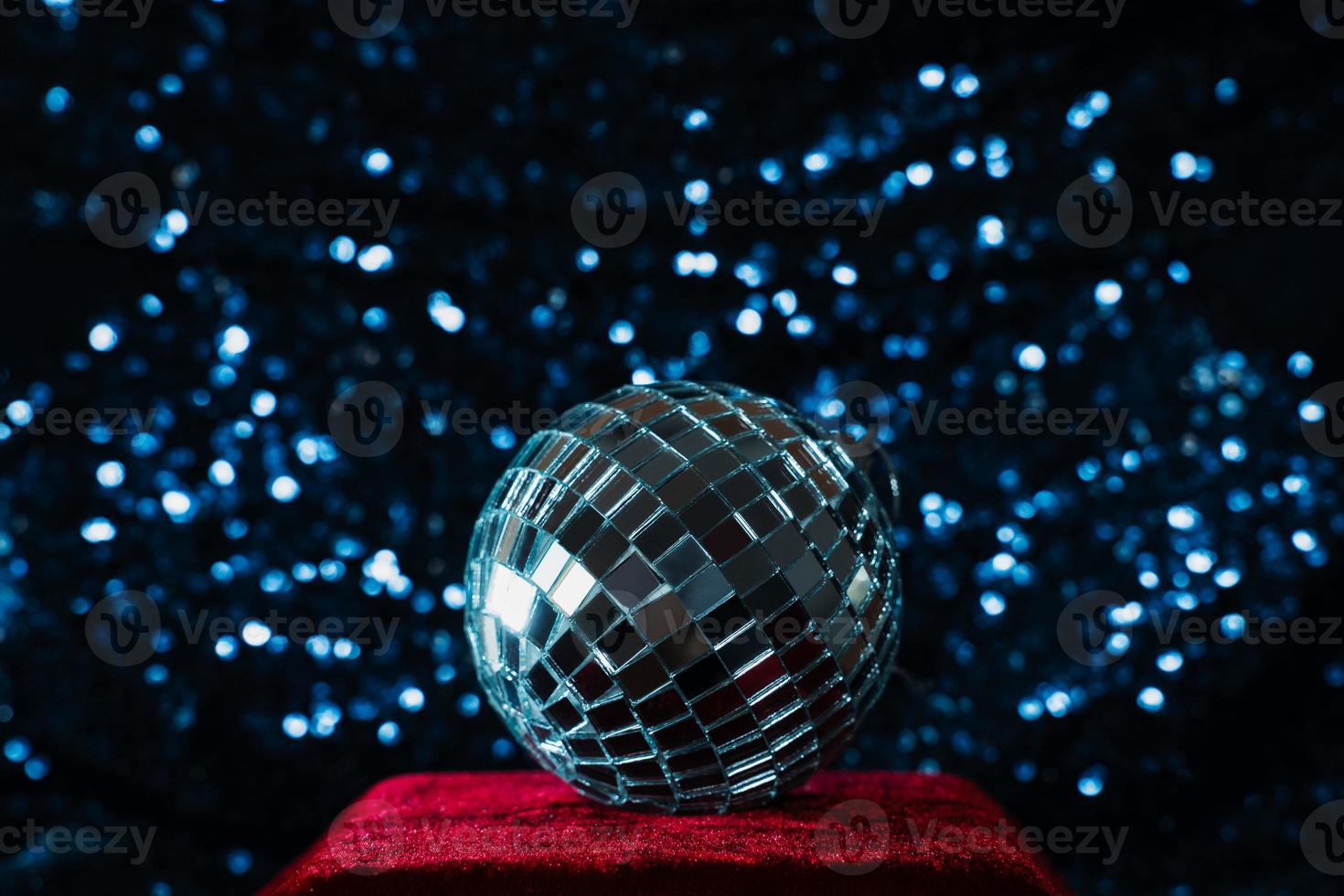 disco ball on red velvet podium on blue sequin background photo