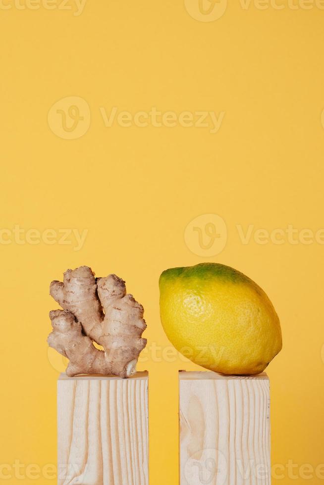 limón y jengibre sobre pedestal de madera sobre fondo amarillo foto