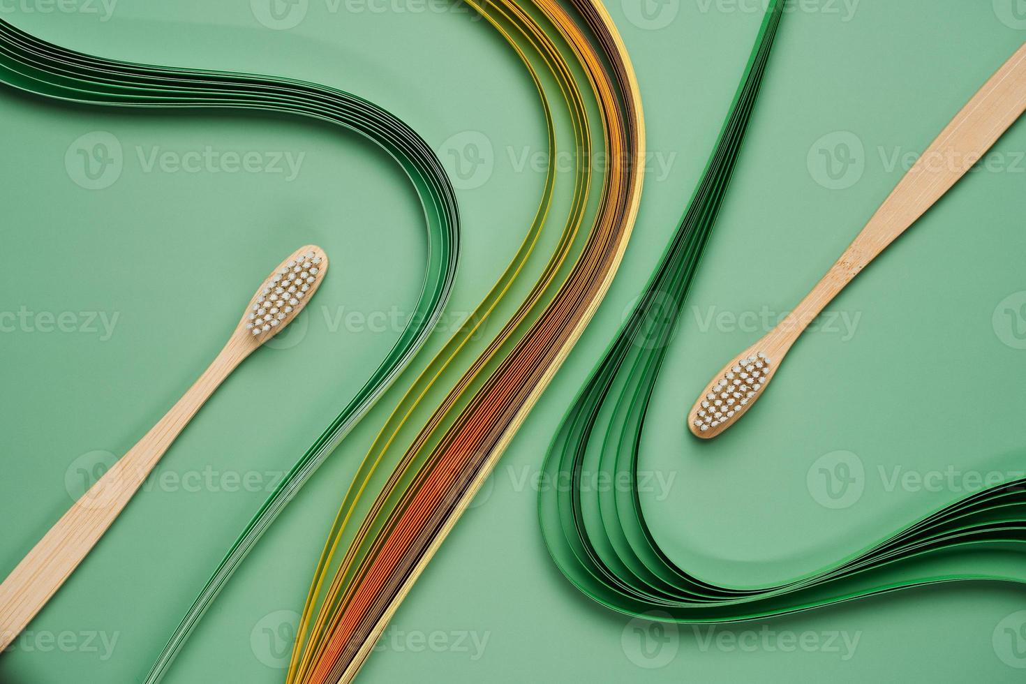 Bamboo toothbrushes on green background with quilling photo