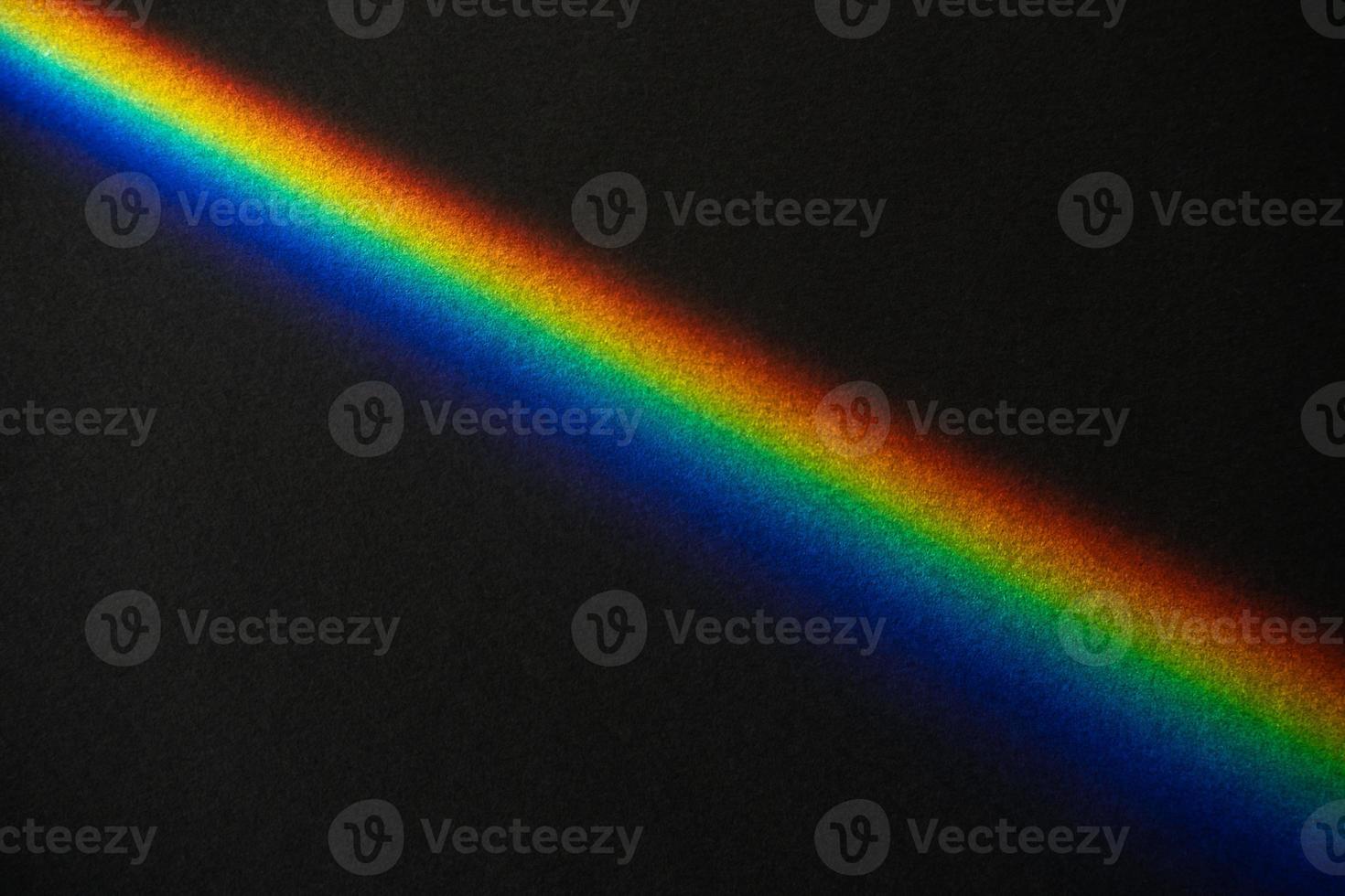 Rainbow streak on black textured paper background photo