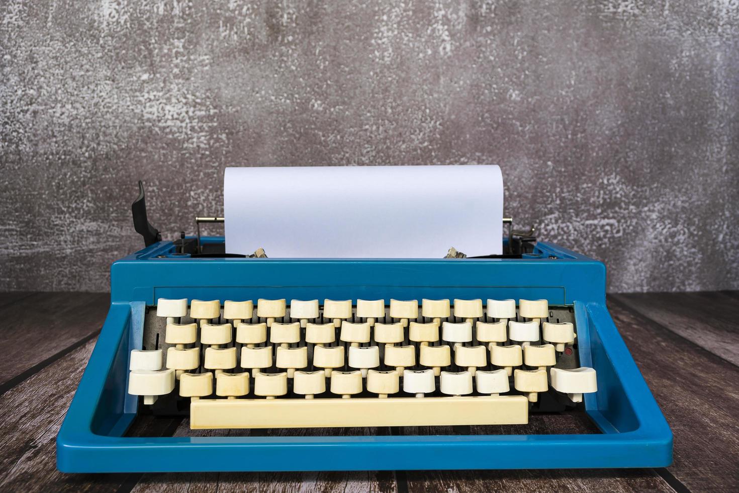 An old blue classic typewriter on wooden desk. Copy space. For text purpose photo